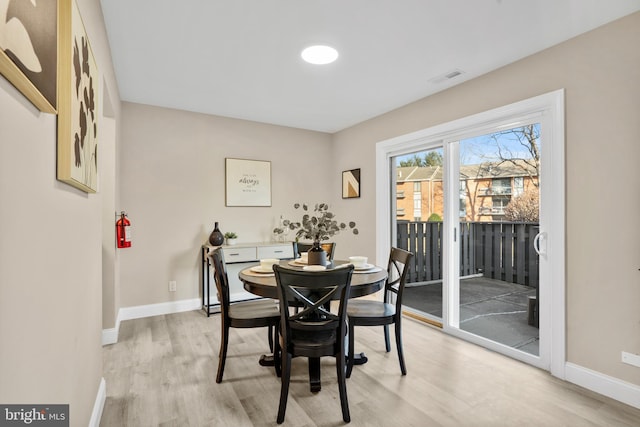 dining area with visible vents, light wood-style flooring, and baseboards