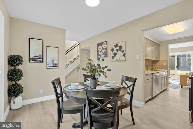 dining space with stairway, light wood-type flooring, and baseboards