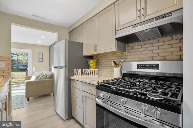 kitchen with visible vents, under cabinet range hood, appliances with stainless steel finishes, light wood-type flooring, and backsplash