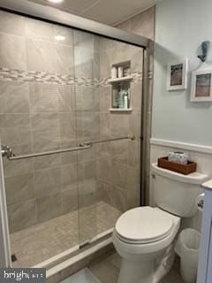 full bathroom featuring tile patterned flooring, a shower stall, toilet, and vanity