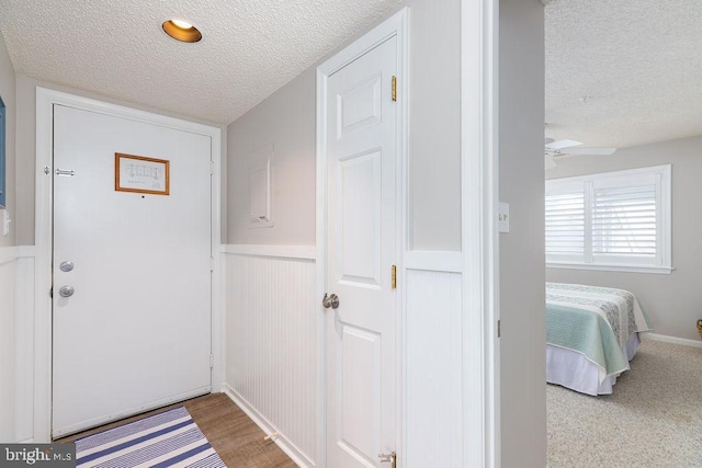 foyer entrance featuring a textured ceiling, ceiling fan, and wood finished floors