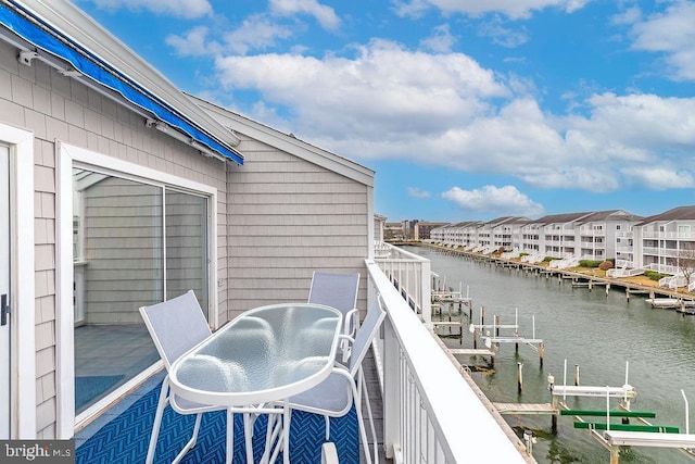 balcony with a dock, a water view, and boat lift