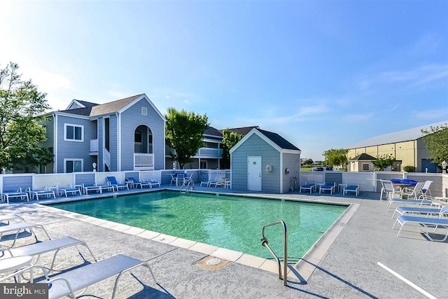 pool with fence, an outdoor structure, and a patio area