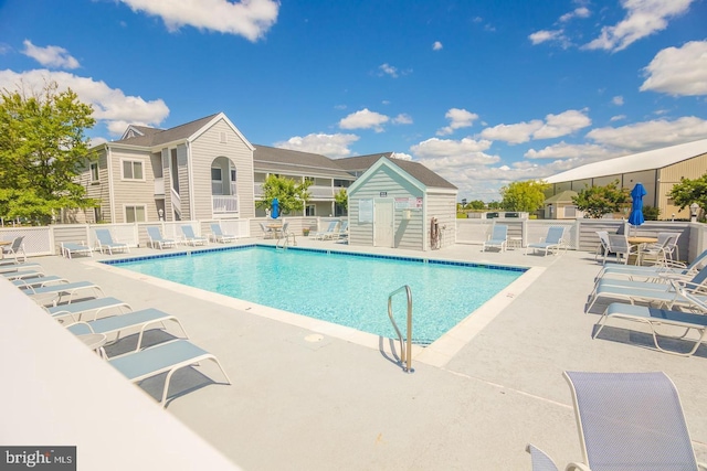 community pool with a patio area and fence