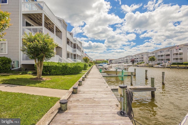 view of dock with a yard, a water view, and a residential view