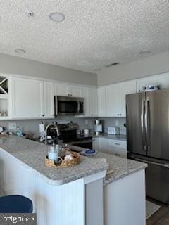 kitchen featuring open shelves, white cabinetry, stainless steel appliances, a peninsula, and light stone countertops