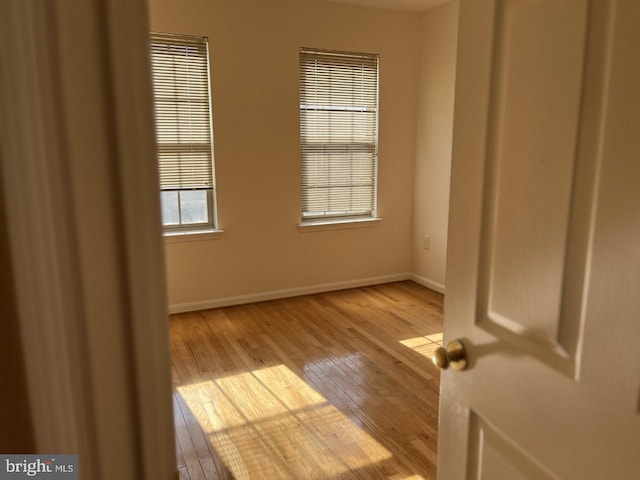 unfurnished room featuring baseboards and light wood-type flooring