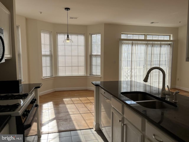 kitchen featuring dark countertops, dishwasher, a wealth of natural light, and a sink