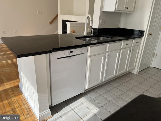 kitchen with white cabinetry, dark countertops, white dishwasher, and a sink