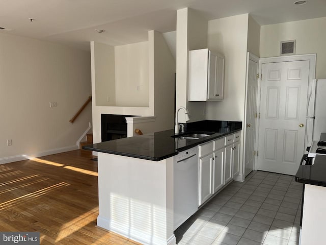 kitchen featuring white appliances, visible vents, a sink, white cabinets, and dark countertops