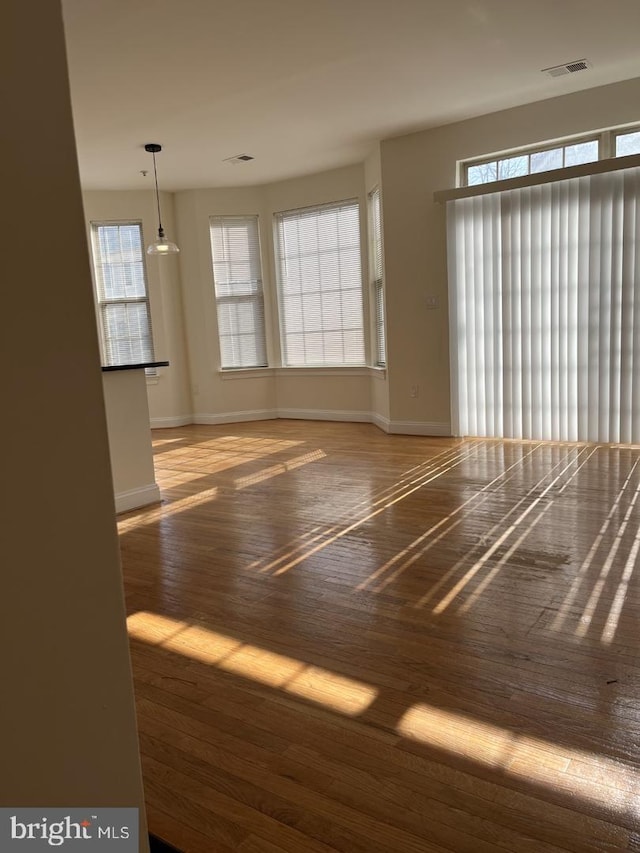 unfurnished room with wood finished floors, baseboards, and a wealth of natural light