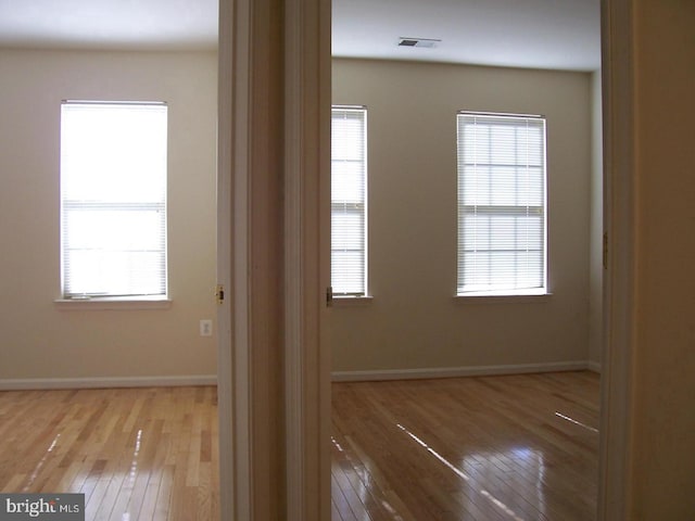 spare room with visible vents, baseboards, and hardwood / wood-style flooring