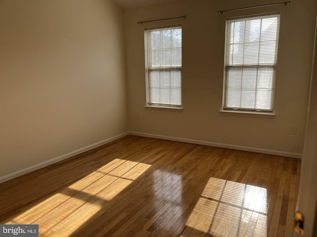 unfurnished room featuring baseboards and wood-type flooring