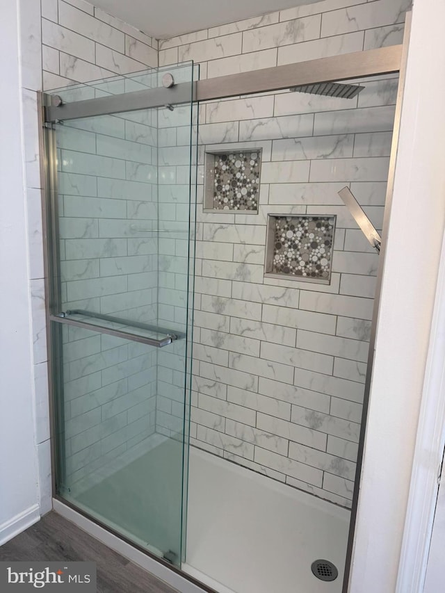 bathroom featuring wood finished floors and a stall shower