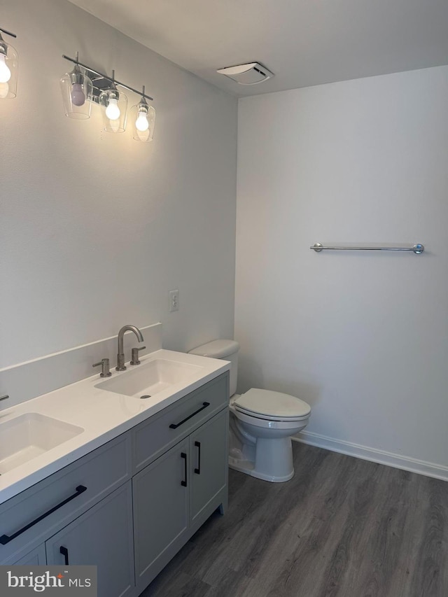 bathroom featuring a sink, visible vents, toilet, and wood finished floors