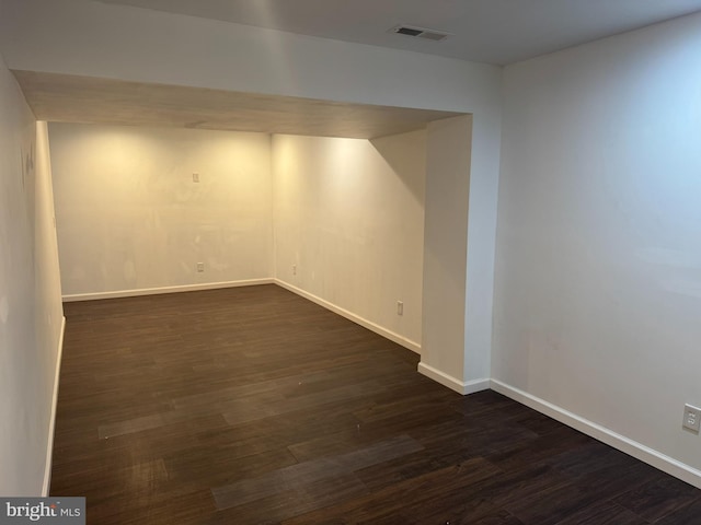 finished below grade area featuring dark wood finished floors, baseboards, and visible vents