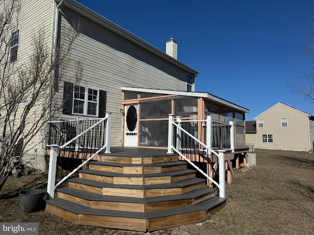 view of front facade featuring a chimney, stairs, and a sunroom