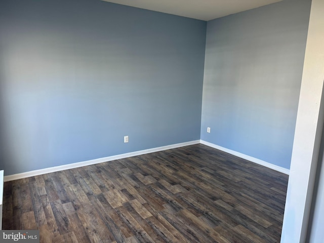 spare room featuring dark wood-type flooring and baseboards