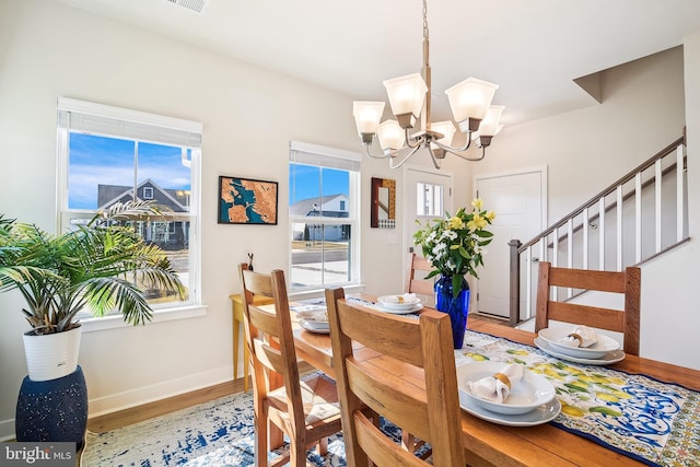 dining room featuring a chandelier, stairway, baseboards, and wood finished floors