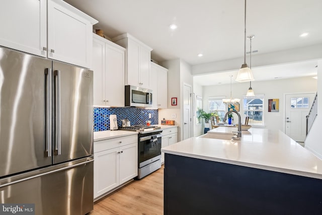 kitchen with a sink, light countertops, light wood-style floors, appliances with stainless steel finishes, and backsplash