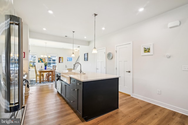 kitchen featuring light countertops, light wood-style floors, freestanding refrigerator, and a sink