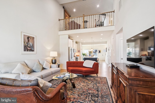 living area featuring visible vents, recessed lighting, a towering ceiling, and wood finished floors