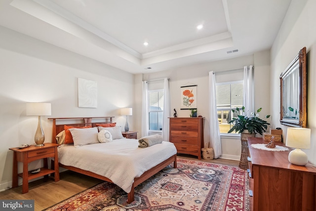 bedroom featuring visible vents, baseboards, light wood finished floors, a tray ceiling, and recessed lighting