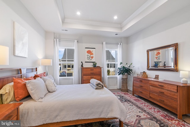 bedroom with recessed lighting, a tray ceiling, and baseboards