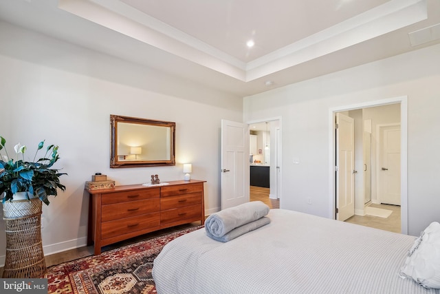 bedroom with recessed lighting, ensuite bathroom, a raised ceiling, and baseboards