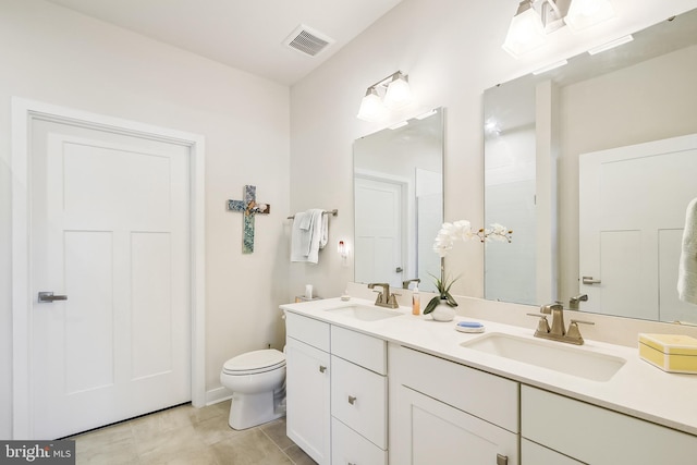 bathroom featuring a sink, visible vents, toilet, and double vanity