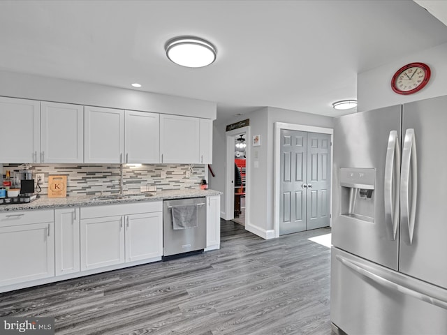 kitchen with a sink, backsplash, appliances with stainless steel finishes, and white cabinets