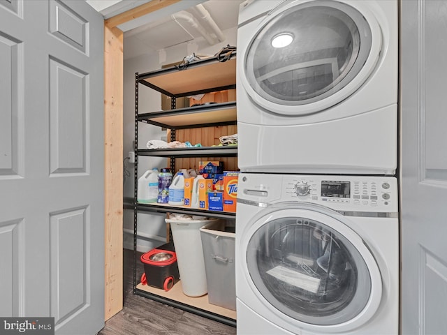 laundry room with laundry area, stacked washer / dryer, and wood finished floors