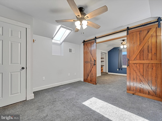 additional living space with visible vents, baseboards, lofted ceiling, a barn door, and carpet flooring