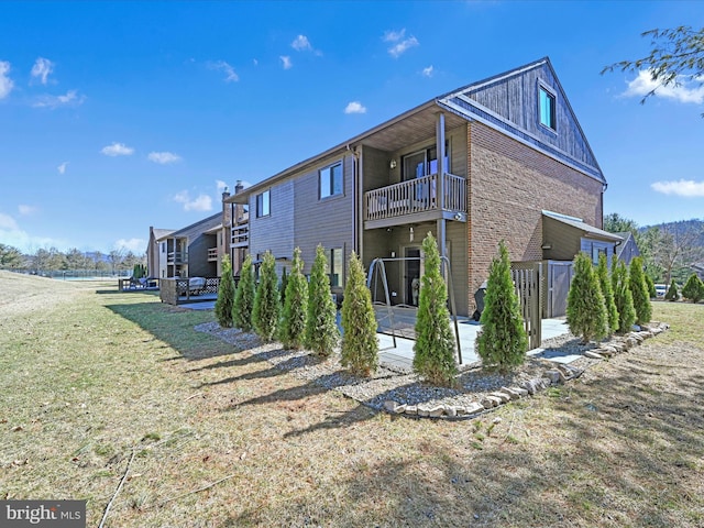 view of home's exterior with brick siding, a lawn, a patio, and a balcony