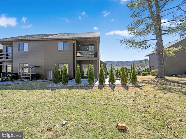 rear view of house with a patio area, a balcony, a lawn, and central AC