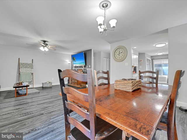 dining space featuring ceiling fan with notable chandelier, baseboards, and wood finished floors