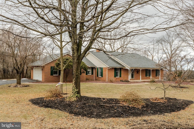 ranch-style house with aphalt driveway, brick siding, an attached garage, and a front yard