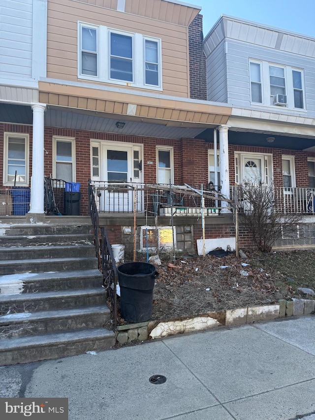 view of property with brick siding, cooling unit, and a porch