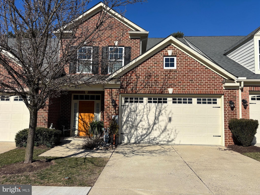 traditional home with a garage, brick siding, driveway, and roof with shingles