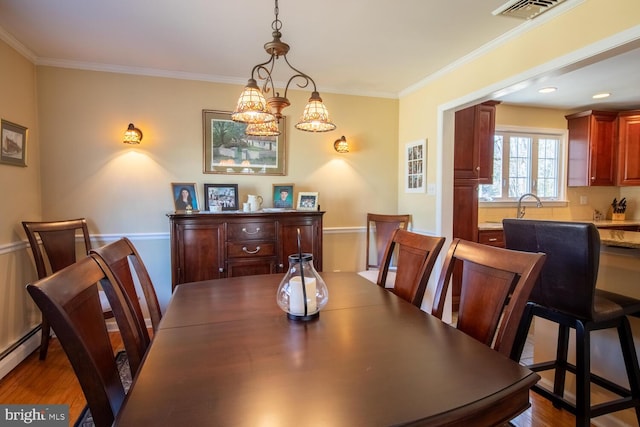 dining space featuring visible vents, crown molding, and wood finished floors