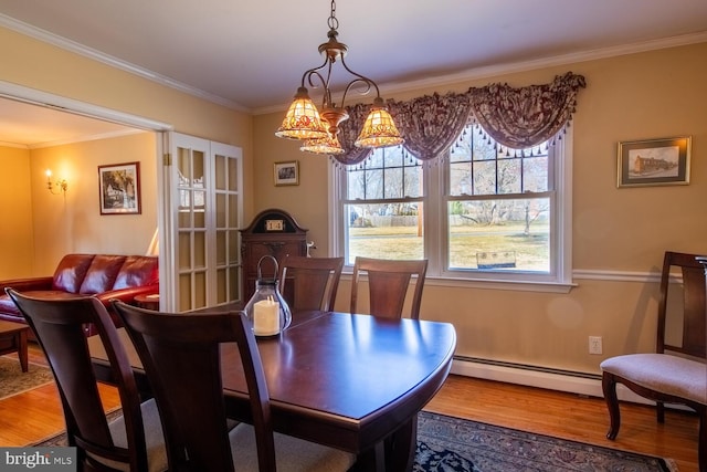 dining room with a notable chandelier, a baseboard radiator, crown molding, and wood finished floors