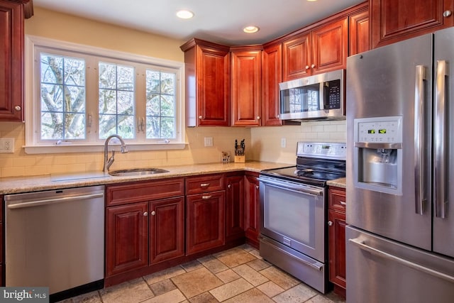 kitchen featuring a sink, tasteful backsplash, stone tile floors, recessed lighting, and appliances with stainless steel finishes