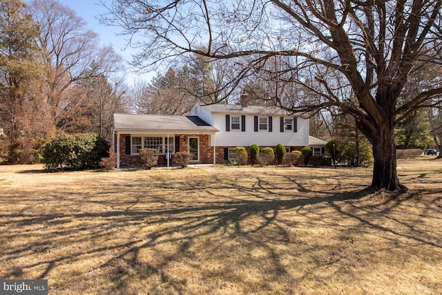 split level home featuring a front lawn, a porch, and brick siding