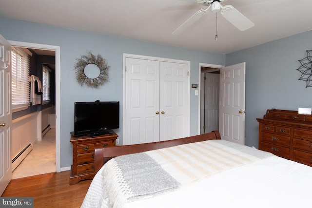 bedroom with a baseboard radiator, a closet, wood finished floors, and a ceiling fan