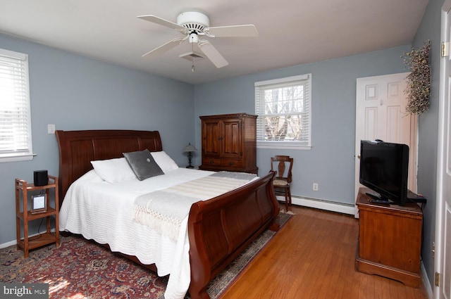 bedroom with visible vents, baseboards, wood finished floors, a ceiling fan, and a baseboard radiator