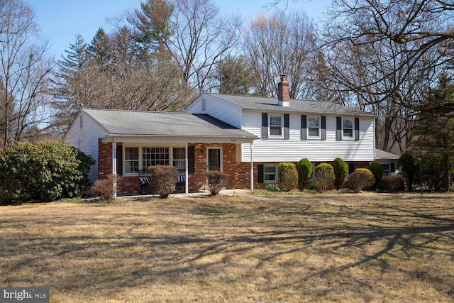 split level home with brick siding, a chimney, and a front lawn