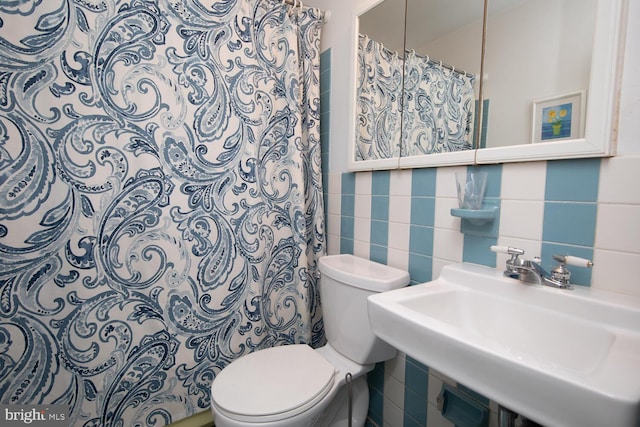 bathroom featuring tasteful backsplash, toilet, tile walls, and a sink