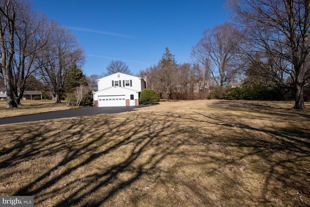 view of home's exterior featuring a lawn, an attached garage, and driveway