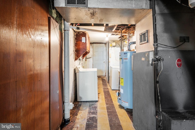 unfinished basement featuring water heater, visible vents, and washing machine and dryer