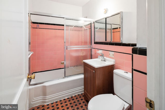 full bathroom featuring enclosed tub / shower combo, toilet, tile walls, and vanity